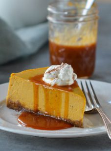 Slice of pumpkin cheesecake dripping with caramel sauce.