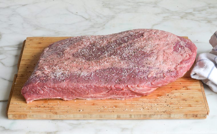 seasoning the brisket with salt and pepper