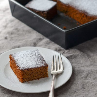 Slice of gingerbread on a plate with a fork.