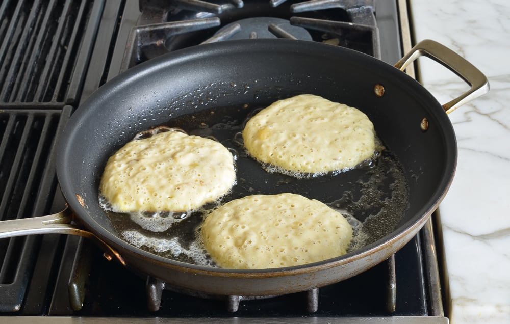 Circles of banana pancake batter in a skillet.