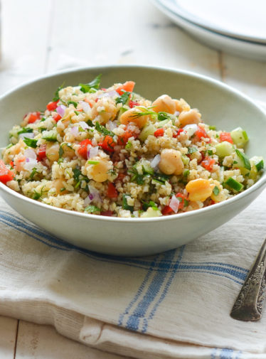 Bowl of bulgur salad with cucumbers, red peppers, chickpeas, lemon, and dill.