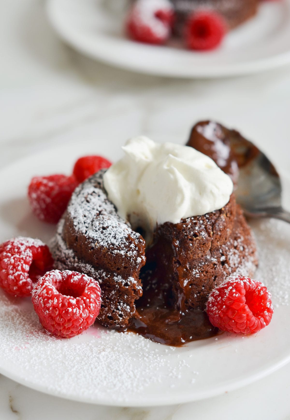 Molten chocolate cake on a plate with raspberries.