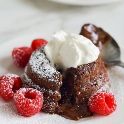 Molten chocolate cake on a plate with raspberries.