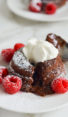 Molten chocolate cake on a plate with raspberries.