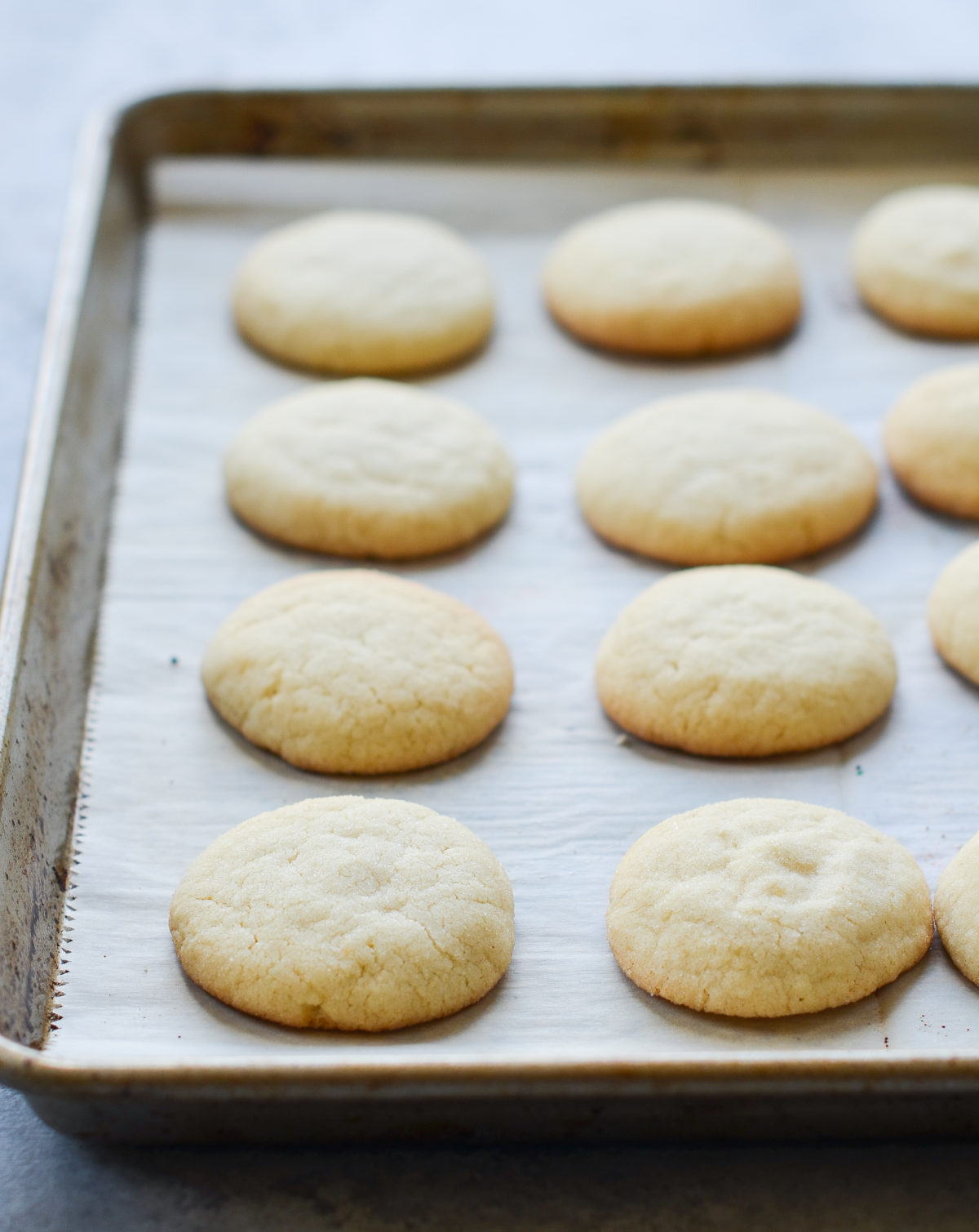 Sugar cookies on a lined baking sheet.