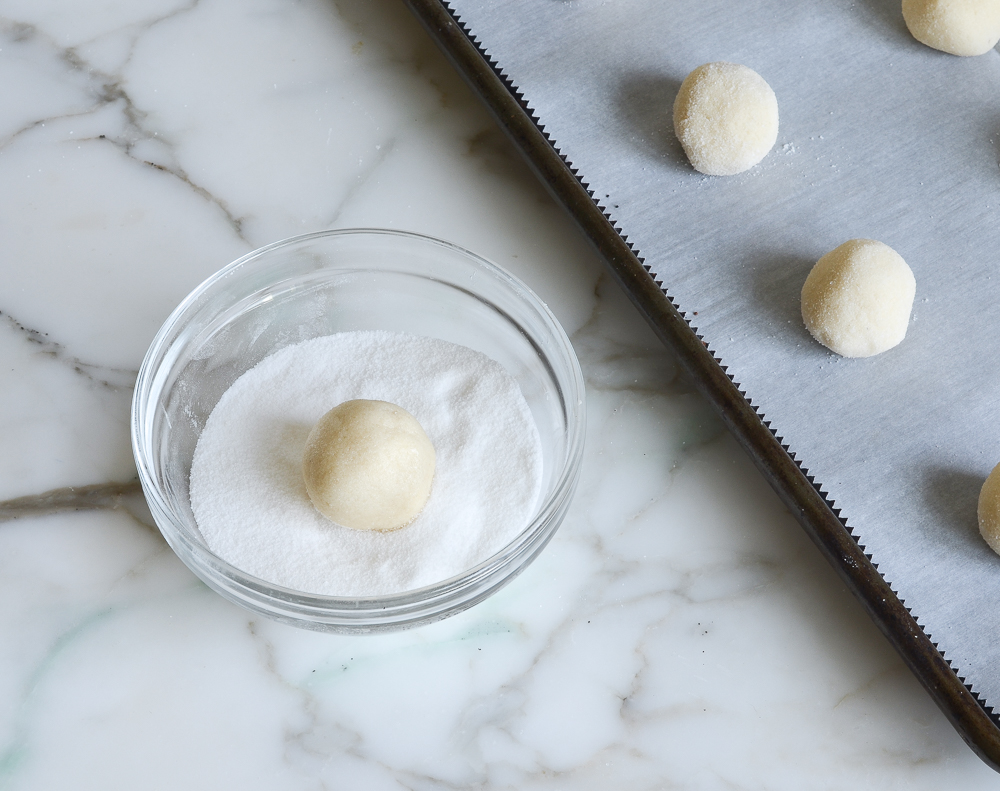 rolling sugar cookie dough balls in sugar 