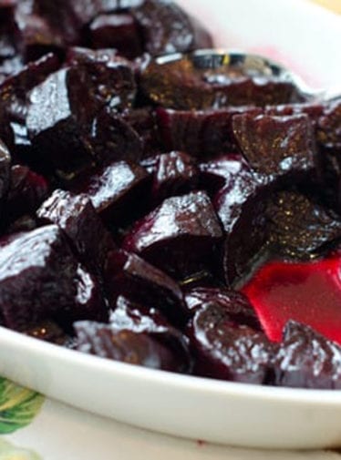 Spoon in a dish of roasted beets.