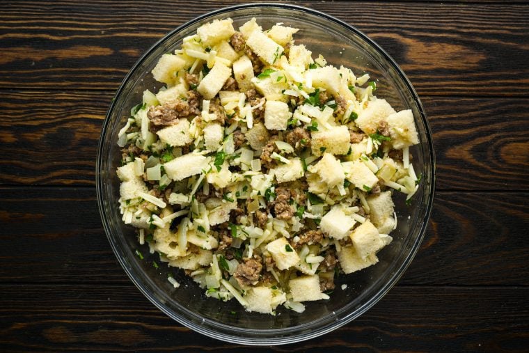 sausage and onions tossed in bowl with other breakfast casserole ingredients