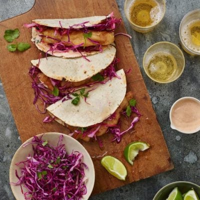Baja fish tacos on a wooden cutting board.