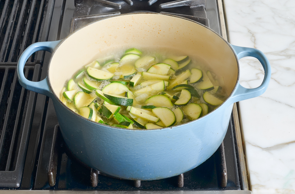adding the zucchini, broth and seasoning to the pot
