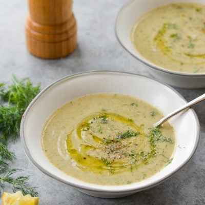 Spoon in a bowl of creamy zucchini soup with walnuts and dill.