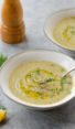 Spoon in a bowl of creamy zucchini soup with walnuts and dill.