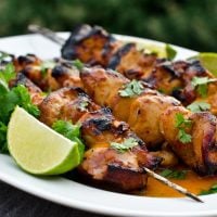 Honey, lime, and sriracha chicken skewers on a plate.