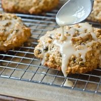 Spoon pouring glaze over oatmeal maple scones with pecans and currants.