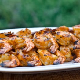 Grilled shrimp skewers with tomato, garlic, and herbs on a plate.