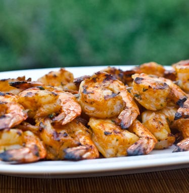 Grilled shrimp skewers with tomato, garlic, and herbs on a plate.