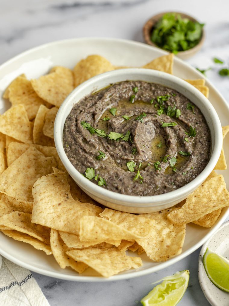 bowl of black bean dip on platter with tortilla chips.