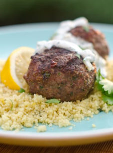 Grilled Moroccan meatballs with yogurt sauce on a bed of couscous.