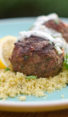 Grilled Moroccan meatballs with yogurt sauce on a bed of couscous.