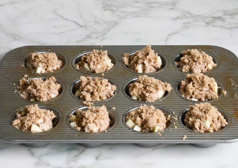 apple muffin batter and brown sugar topping in muffin pan