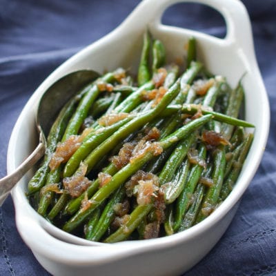 Spoon in a dish of French green beans with shallots.
