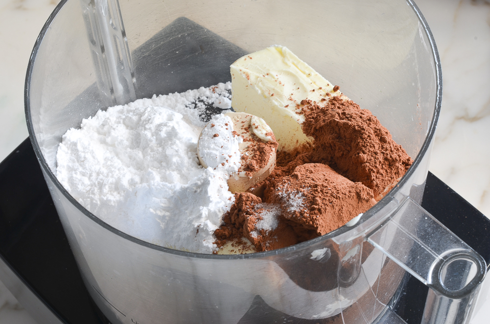butter, confectioners sugar, and cocoa powder in food processor