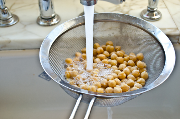 Running water rinsing chickpeas in a sieve.