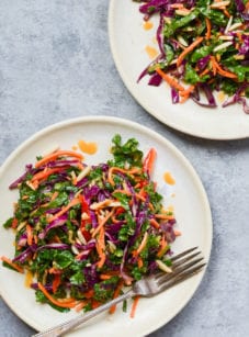 Kale salad with ginger peanut dressing on plates.