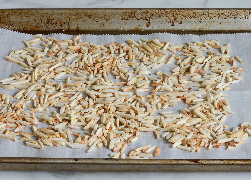 Toasted almonds on a lined baking sheet.