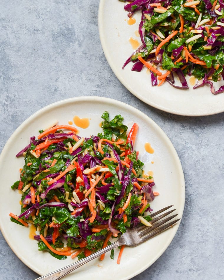 Kale salad with ginger peanut dressing on plates.