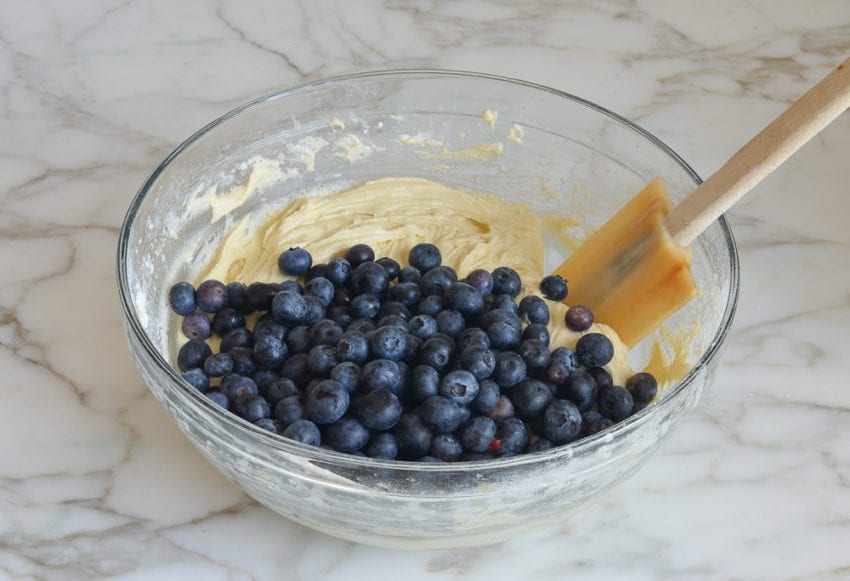 Blueberries in a bowl with muffin batter.