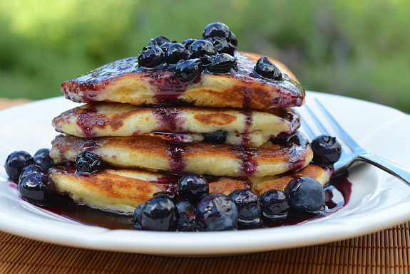 Stack of blueberry buttermilk pancakes topped with blueberry maple syrup.