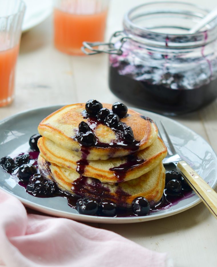 Stack of blueberry pancakes drizzled with blueberry-maple syrup.