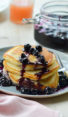 Stack of blueberry pancakes drizzled with blueberry-maple syrup.