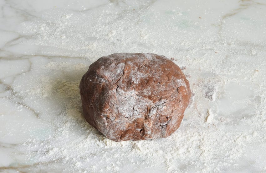 Ball of chocolate dough on a floured counter.