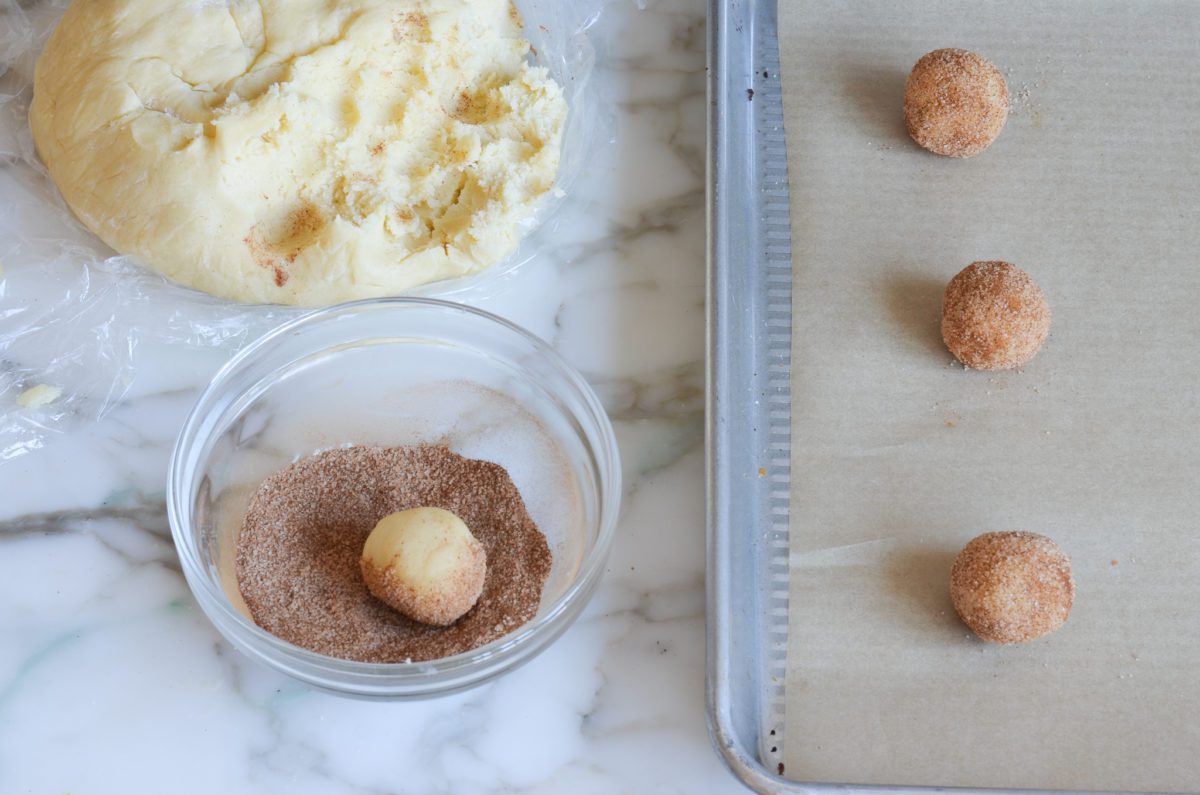 rolling snickerdoodle balls in cinnamon sugar
