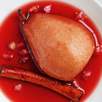 Plate with a baked pear in spiced pomegranate syrup.