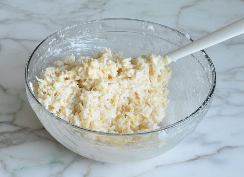 Spatula folding egg whites into a coconut mixture.