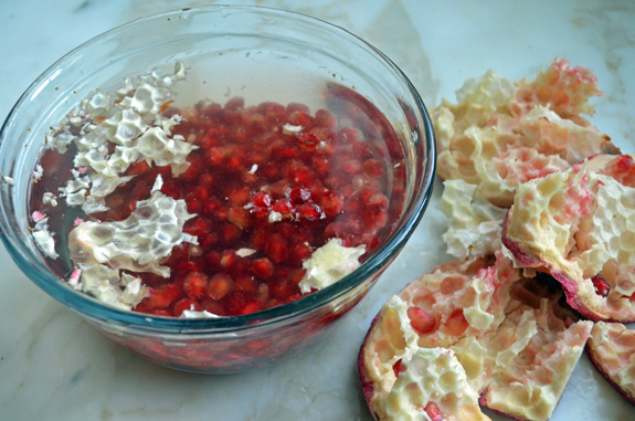 Pomegranate seeds in a bowl of water.