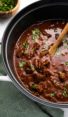 Wooden spoon in a pot of chili con carne.
