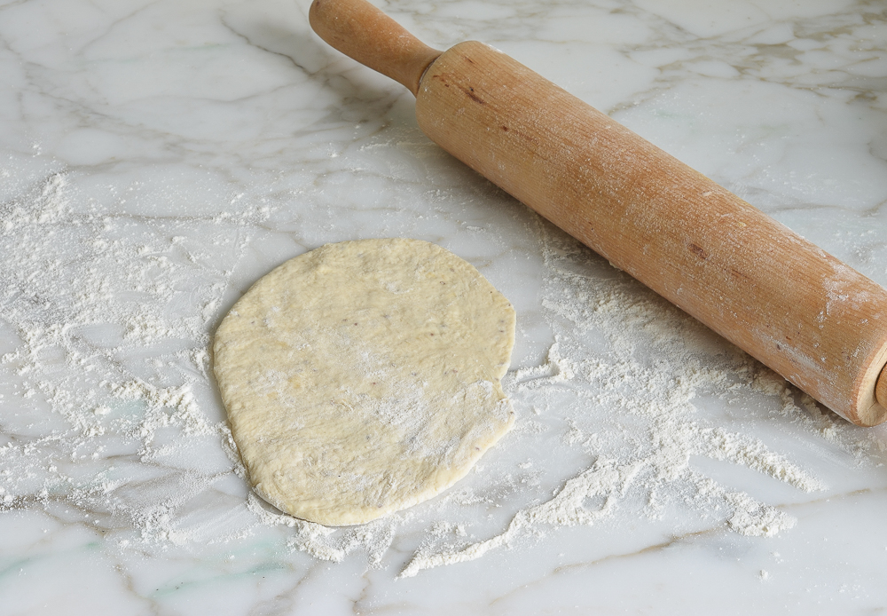 Flattened dough with a rolling pin.