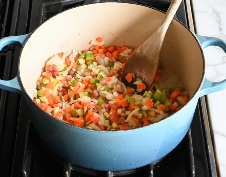 adding the onions, carrots, and celery to the pot.