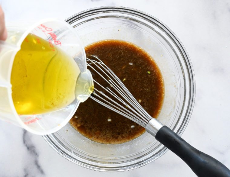 pouring in the olive oil while whisking