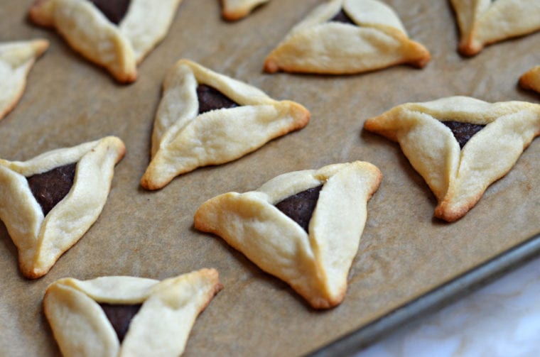 Chocolate-filled hamantaschen on a lined baking sheet.