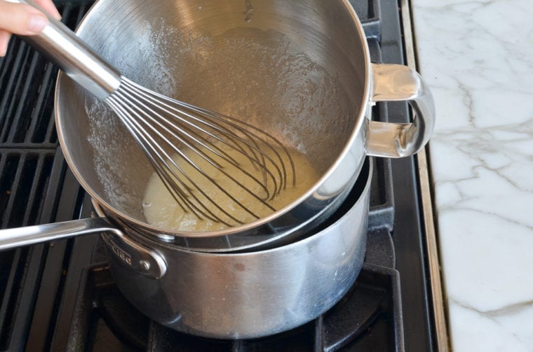 whisking egg whites and sugar over simmering water