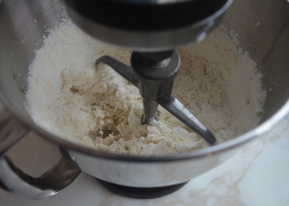 Flour added to a stand mixer with a butter mixture.