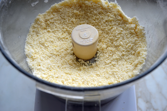 Pale yellow and crumbly mixture in a food processor.