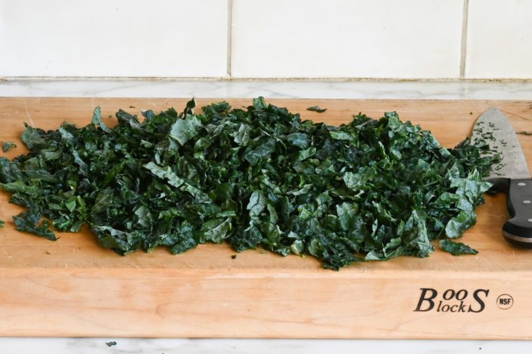 Sliced kale on a wooden cutting board.