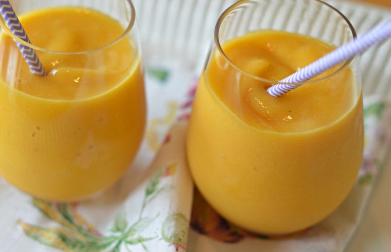 Peach mango smoothies in two small glasses.