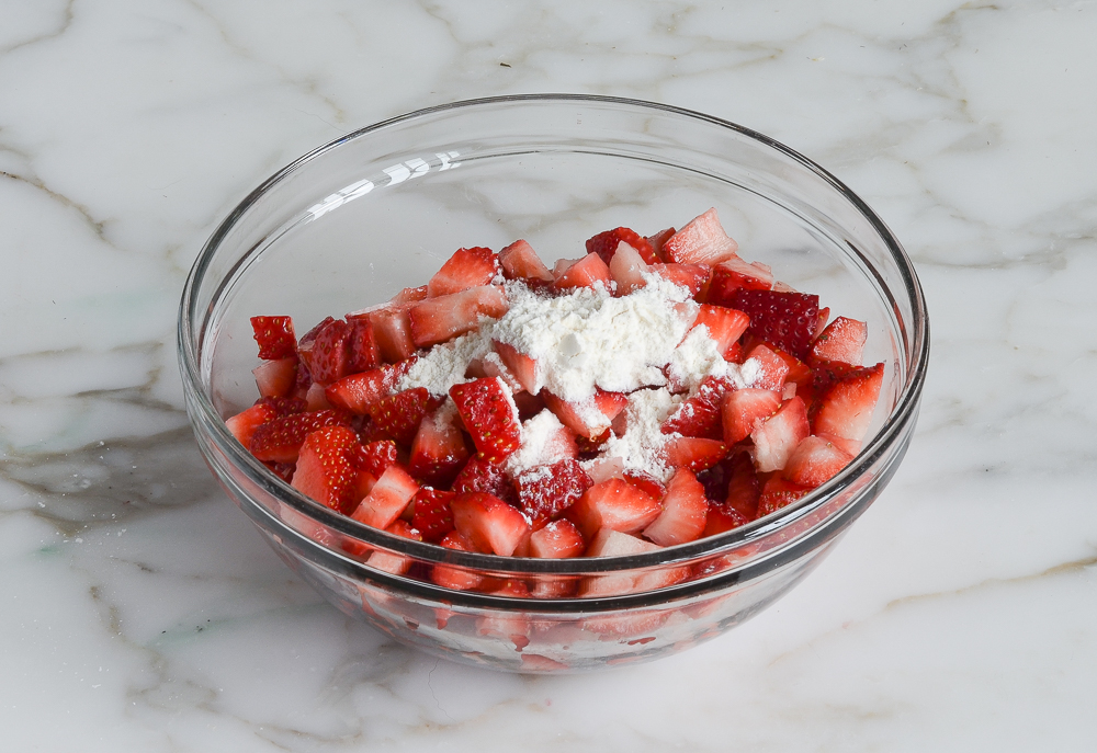 adding flour to the diced strawberries